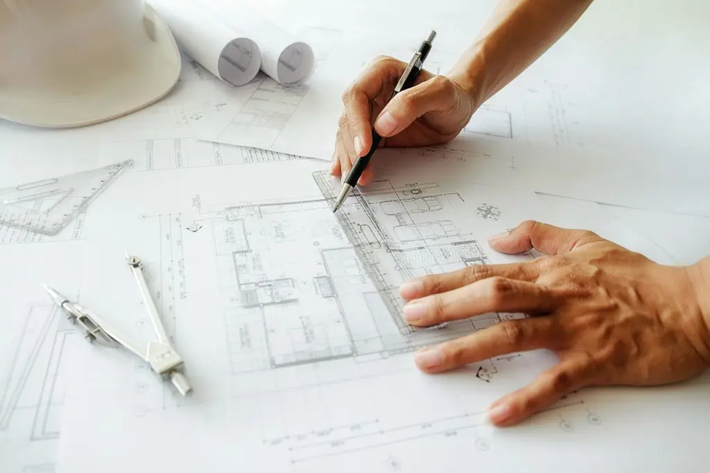 Hands of Engineer working on a custom home blueprint.