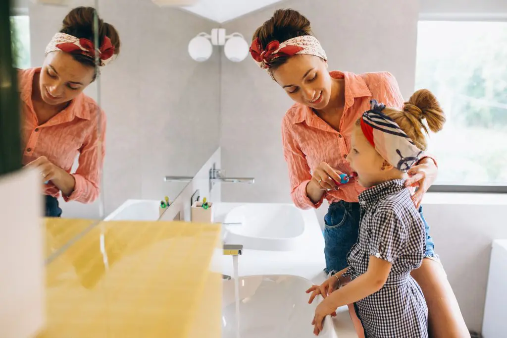 Mom helping daughter in a stylish looking kids bathroom.