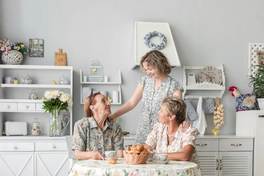 Two women visiting with a grandmother living in her bright and airy mother-in-law suite.