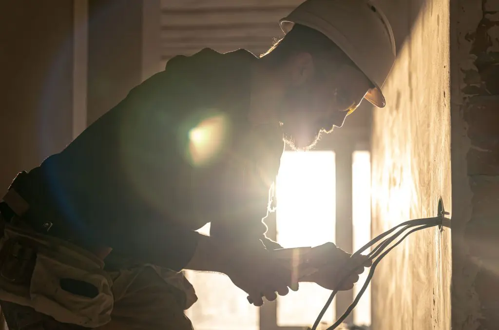 A construction electrician cuts a voltage cable during a repair.