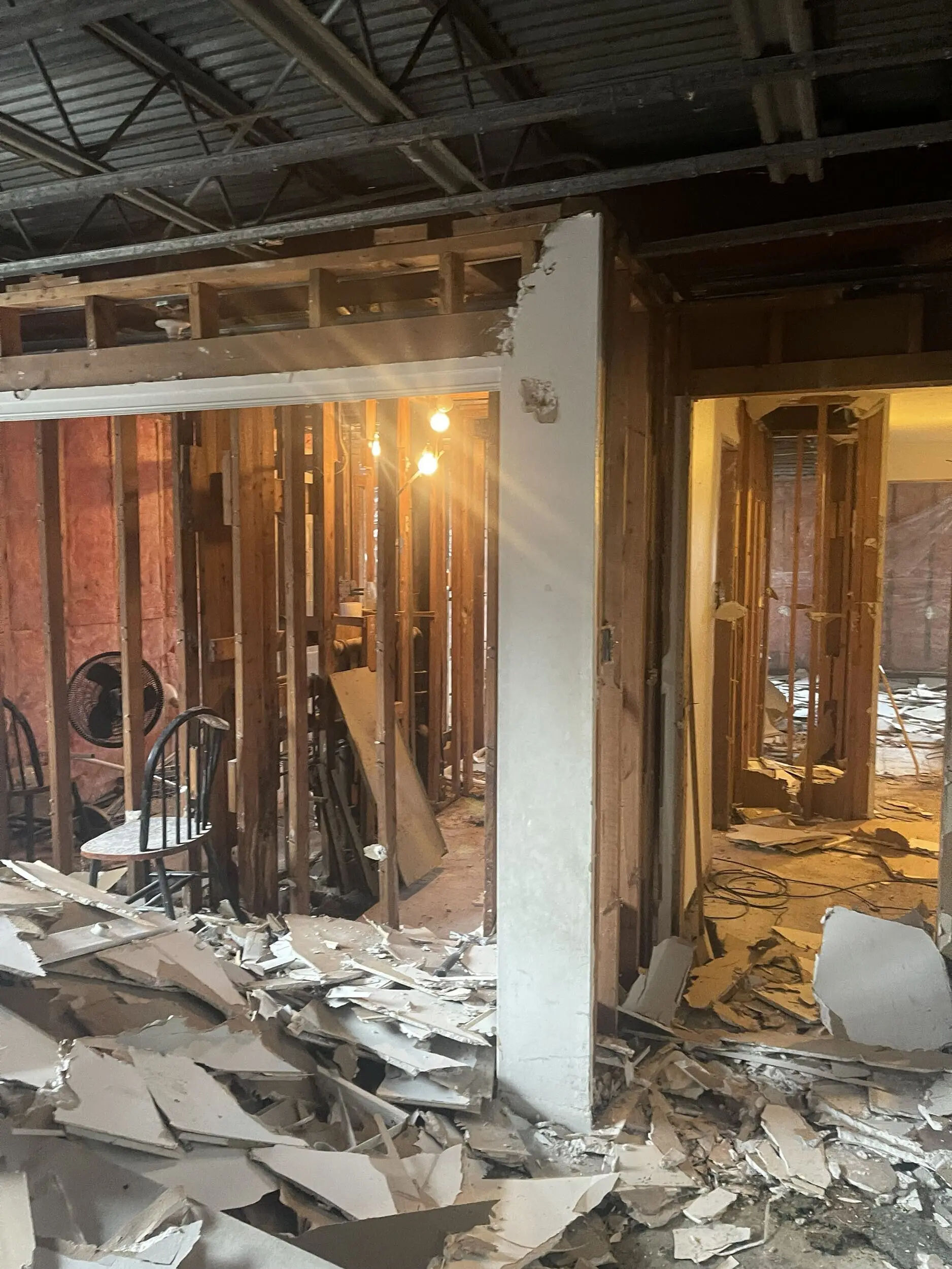 Doorway view of drywall debris and exposed studs