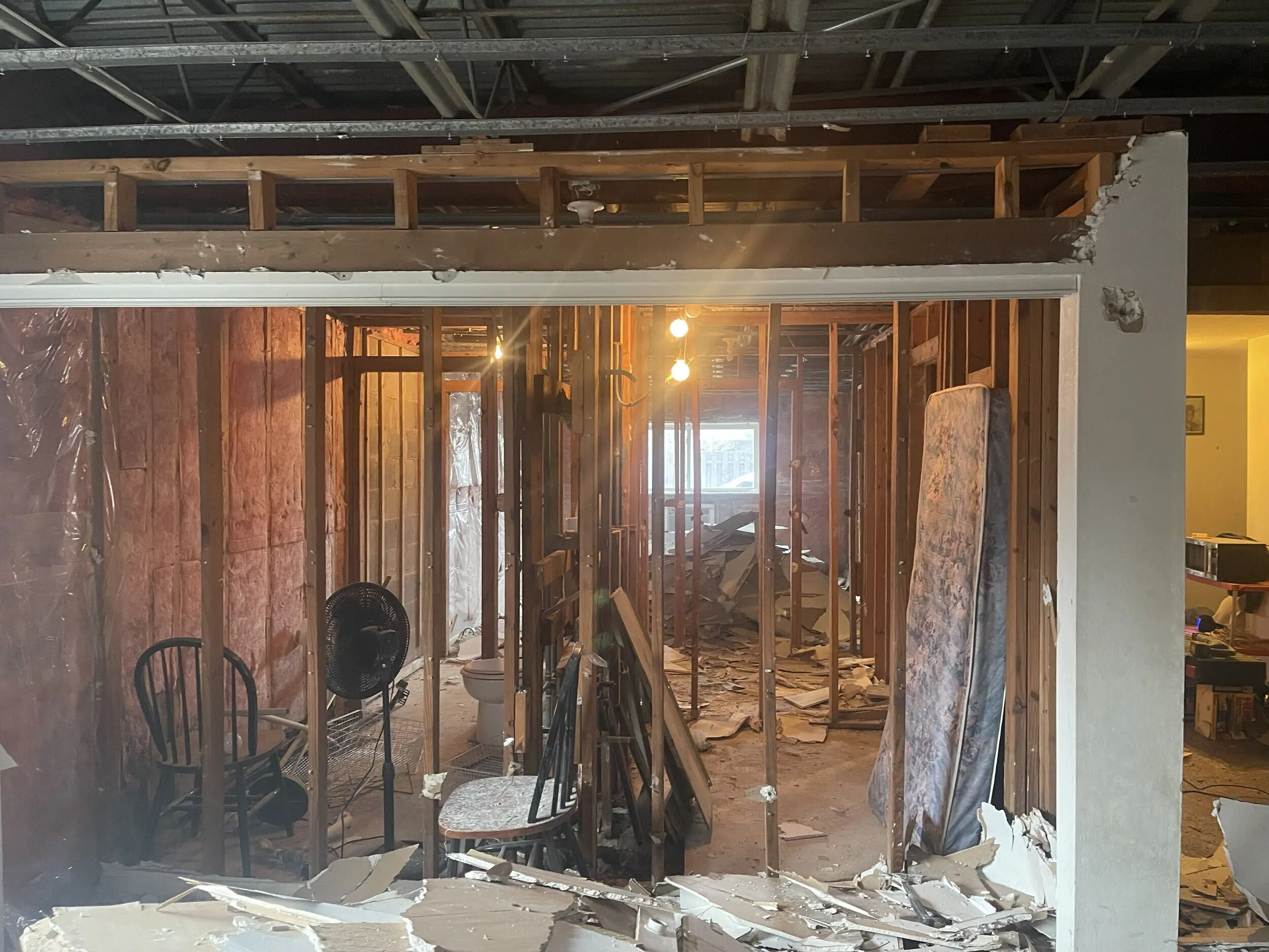 Gutted walls and bathroom with demolition debris on the floor