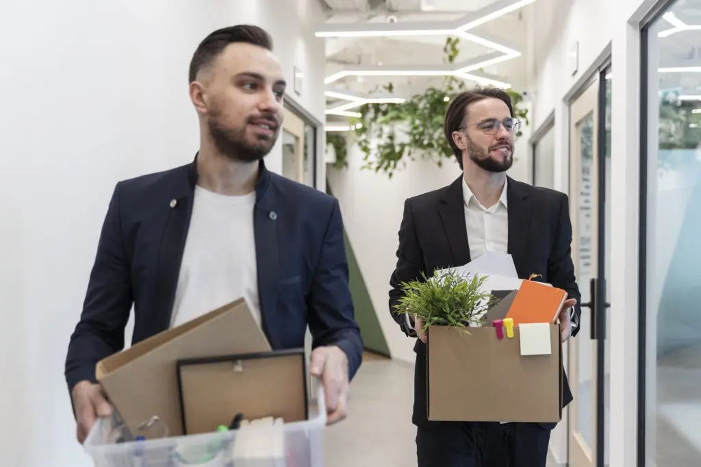 Two men remove personal items from their offices in preparation for an office renovation.